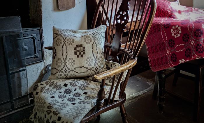 A rocking chair adorned with a blanket and cushion.